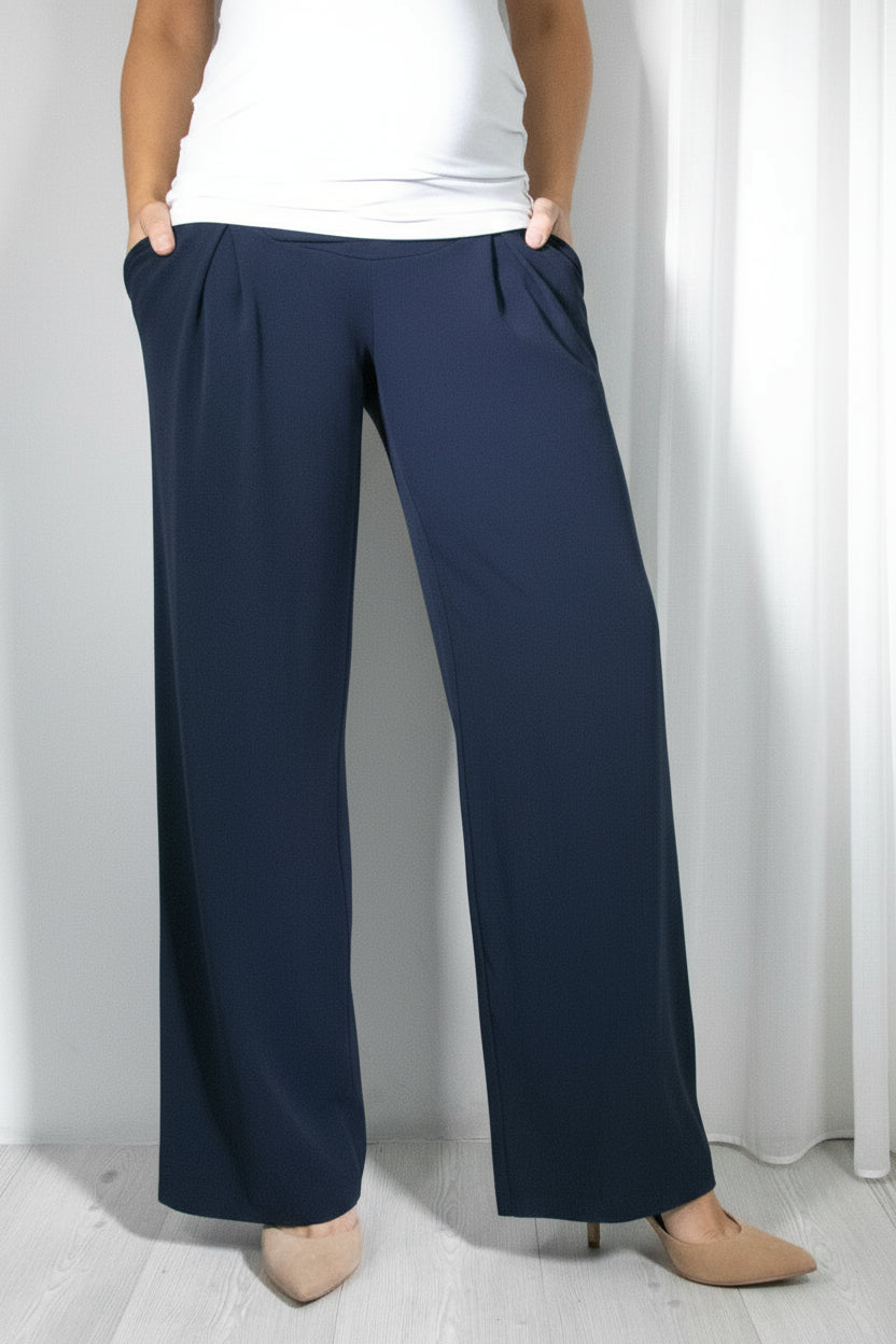 A pair of dark blue maternity pants with a wide flare, featuring two pockets on the sides and elastic waistband, worn by a pregnant woman.
Temno modre nosečniške hlače s široko širino, z dvema žepoma ob straneh in elastičnim pasom, ki jih nosi nosečnica.