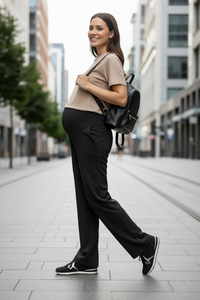 Woman walking on a city street wearing black pants, a beige top, and black sneakers with a black backpack.